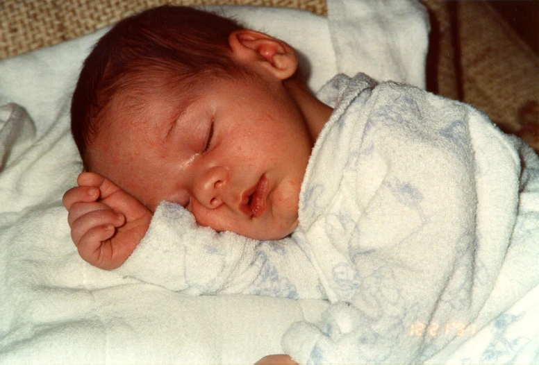 a close up of a baby laying on top of a bed