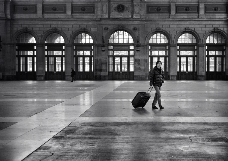 a black and white po of a woman with a suitcase in a large building