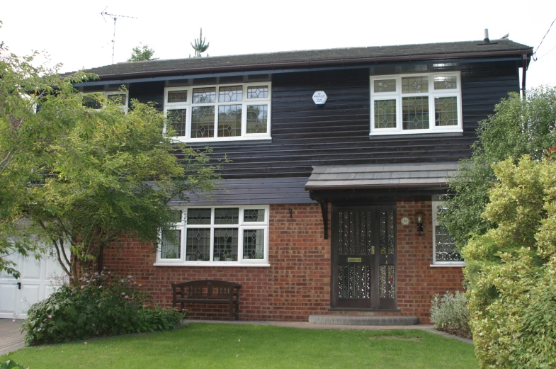 a brick house has trees and shrubs around it