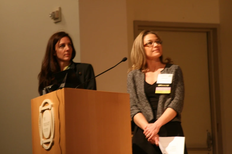 a woman and a lady are talking into a podium