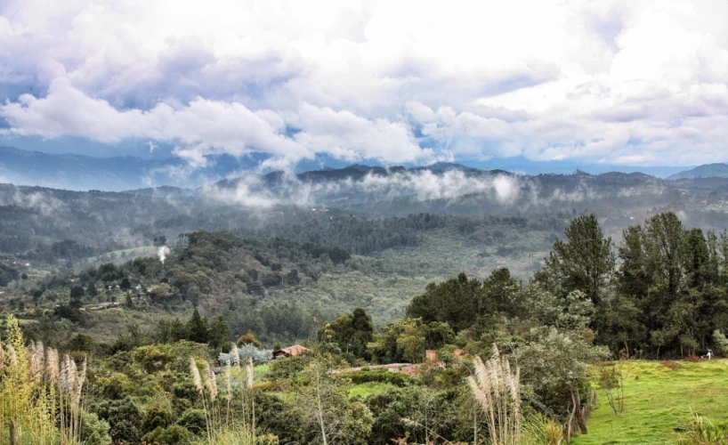 a scenic view of green mountain landscape with thick clouds