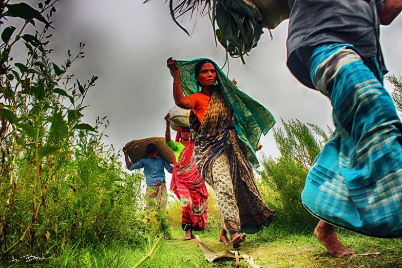 two women carrying large bananas walking through a grass covered forest