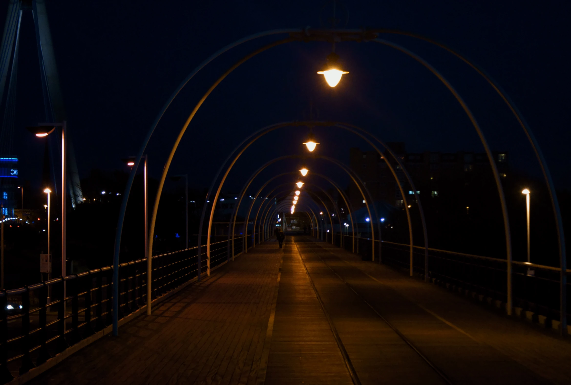 a walkway with lights hanging above at night