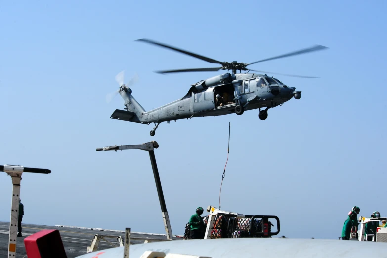 a helicopter flying next to a ship and loading cargo on top of it