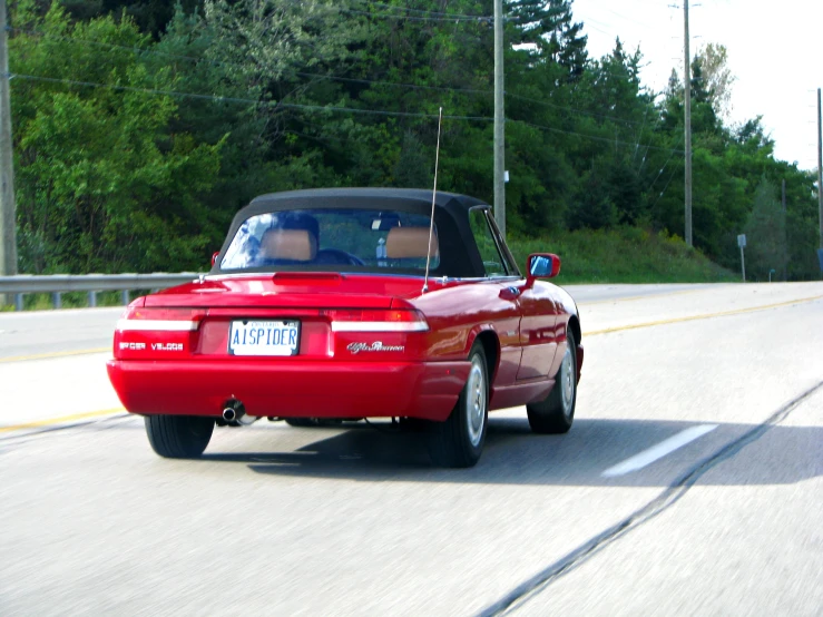 a red sports car driving down a rural road