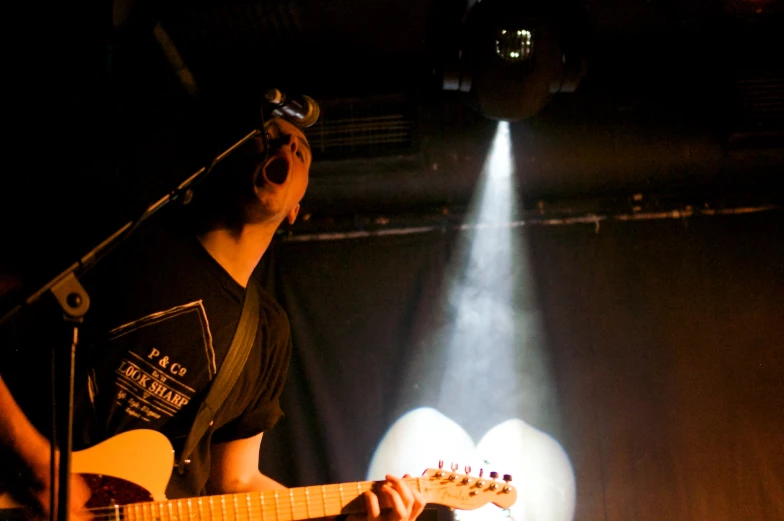 a man holding a guitar in front of two spotlights