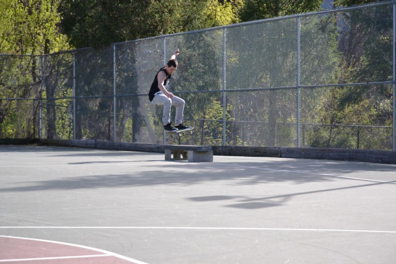 a boy on a skateboard does tricks over a concrete bench