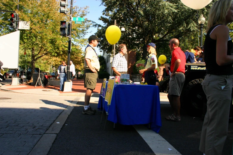 a crowd gathered near a street corner selling balloons