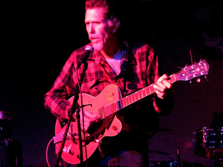 a man playing guitar on stage at a bar