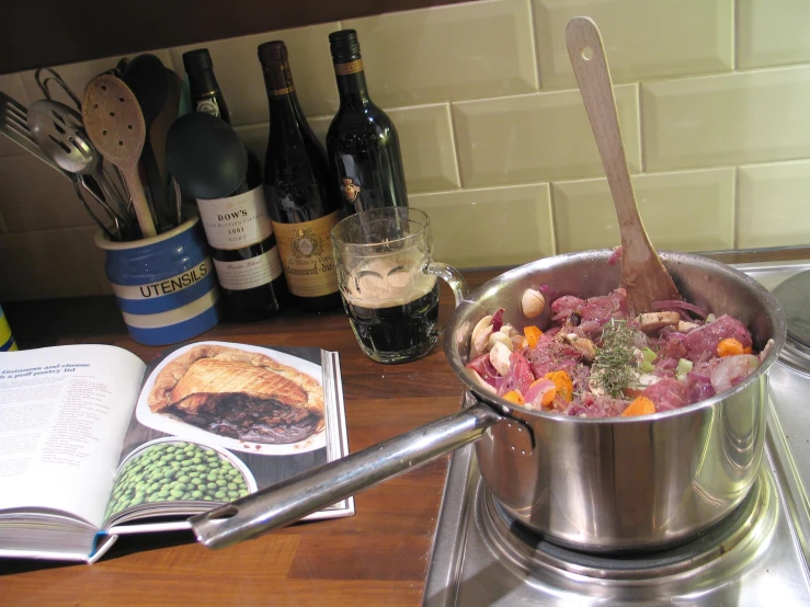 there are bottles of wine, a cookbook, and food in the sink