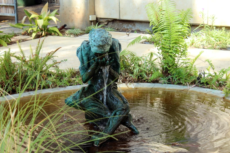 a little statue sitting in some water near a plant