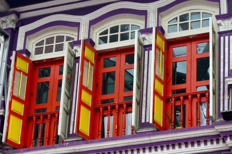 a colorful building has three windows and yellow shutters