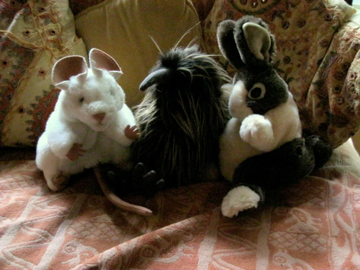 two stuffed animals on a couch with a stuffed mouse and a real rat