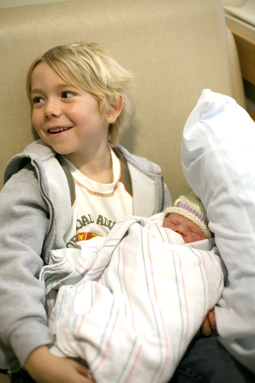 a child sits in a chair holding a baby