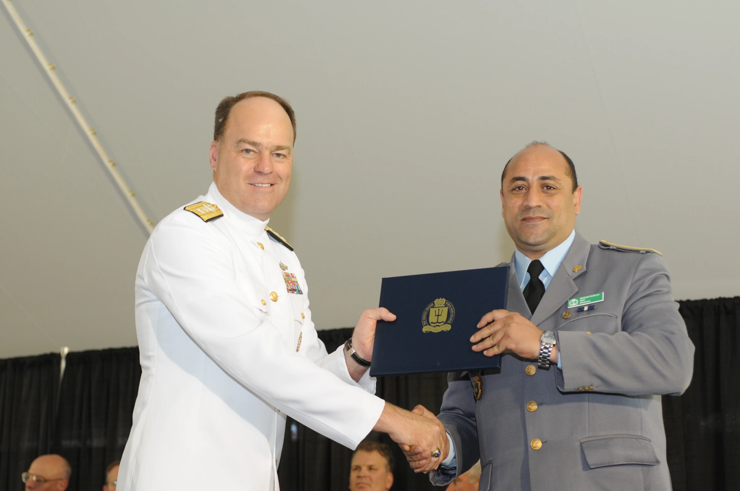 two men in uniform shaking hands during a ceremony