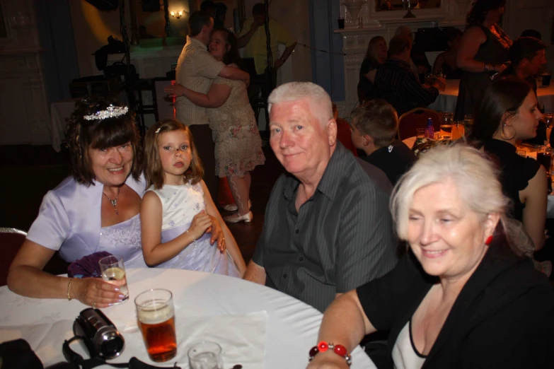 an older man sitting next to a group of women at a table