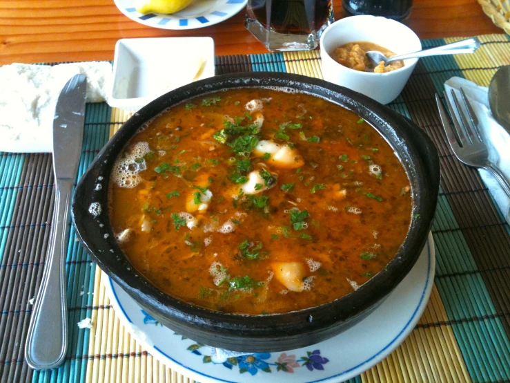 the bowl is full of food and a spoon near other plates and utensils