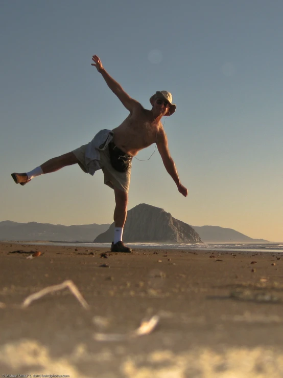 a man doing tricks on the beach at sunset