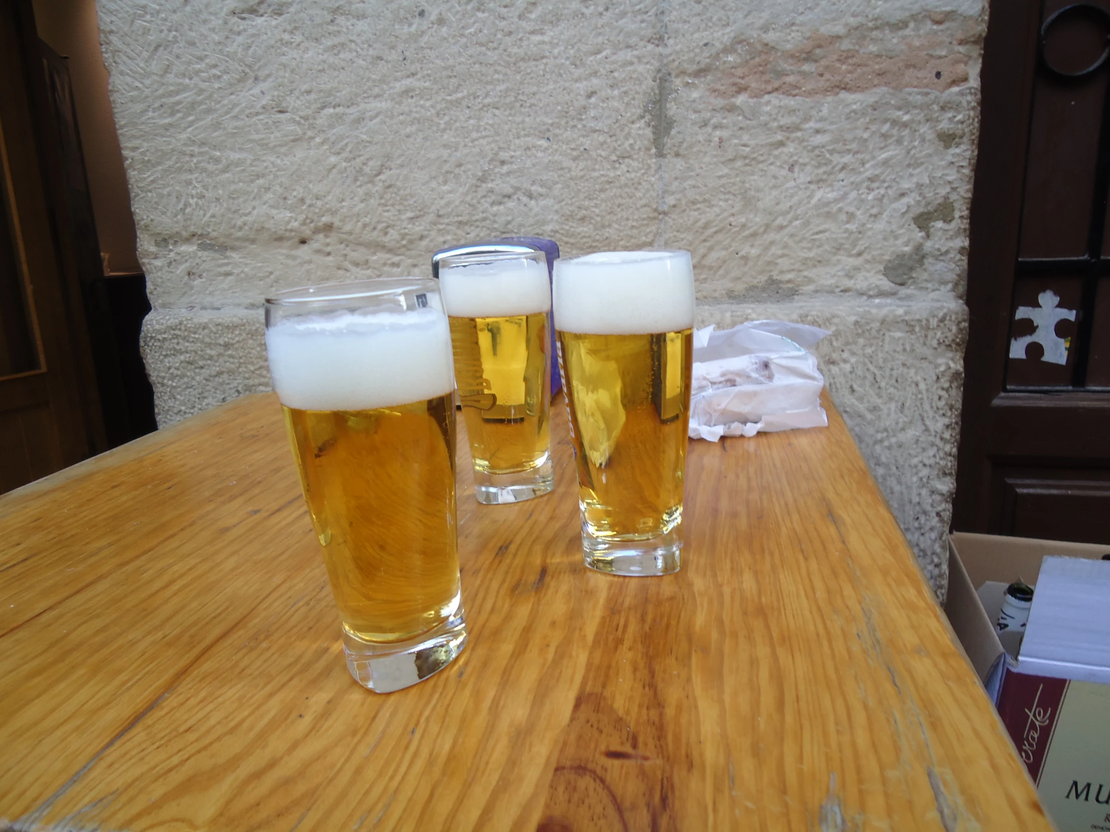 three glasses of beer sitting on top of a wooden table