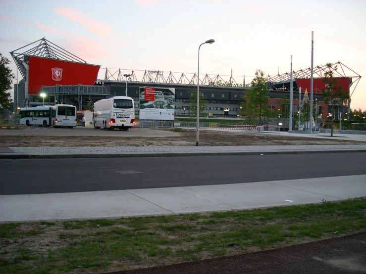 two buses driving down a street near a stadium