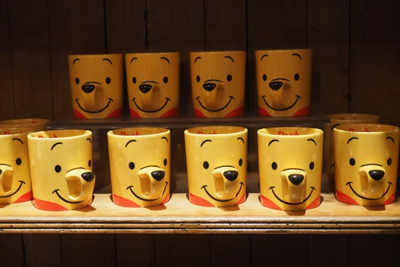 a row of mugs are on display with faces