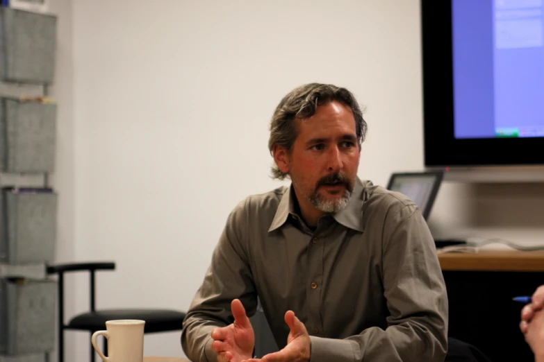 a man talking to a person at a conference room table