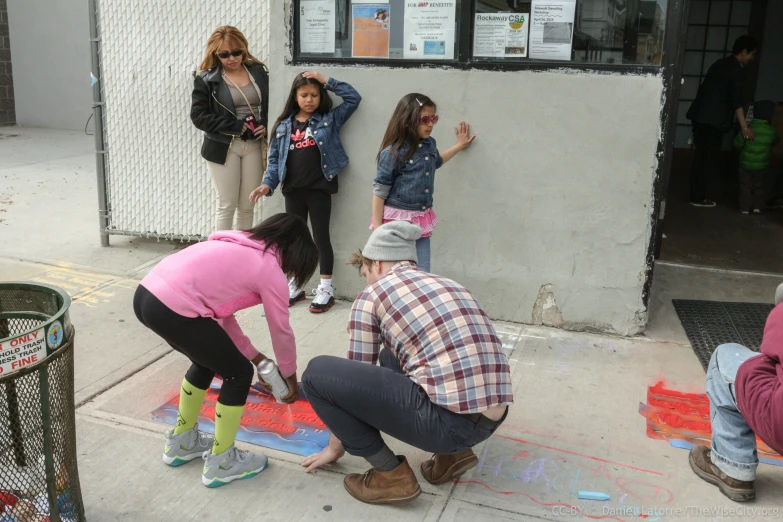 four young women painting the sidewalk with chalk