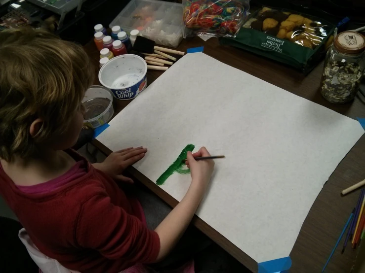 a child painting an art piece on a white sheet of paper