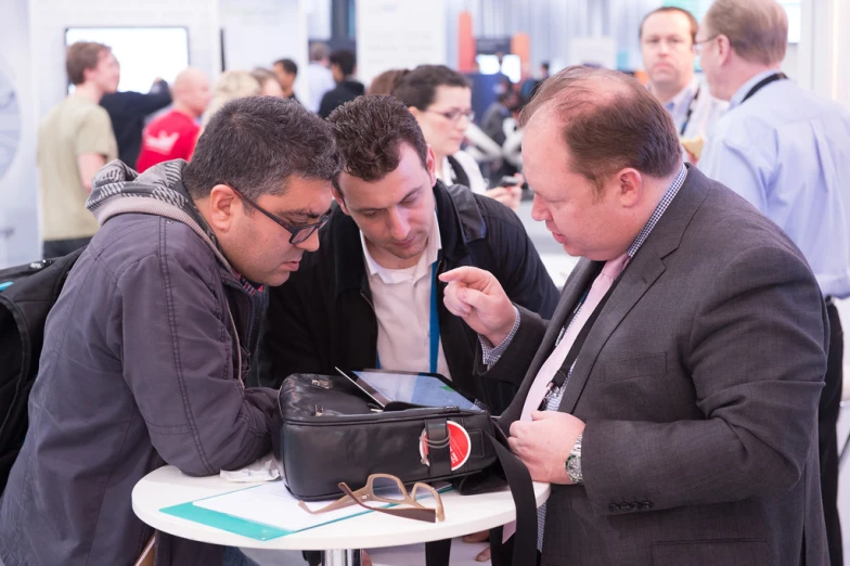 three men are looking at an ipad together