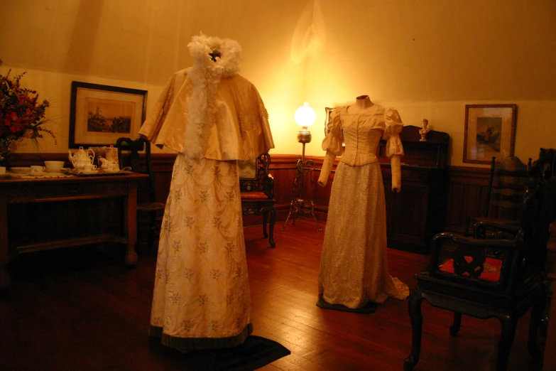 two mannequins dressed in period dresses standing next to each other in the middle of a room