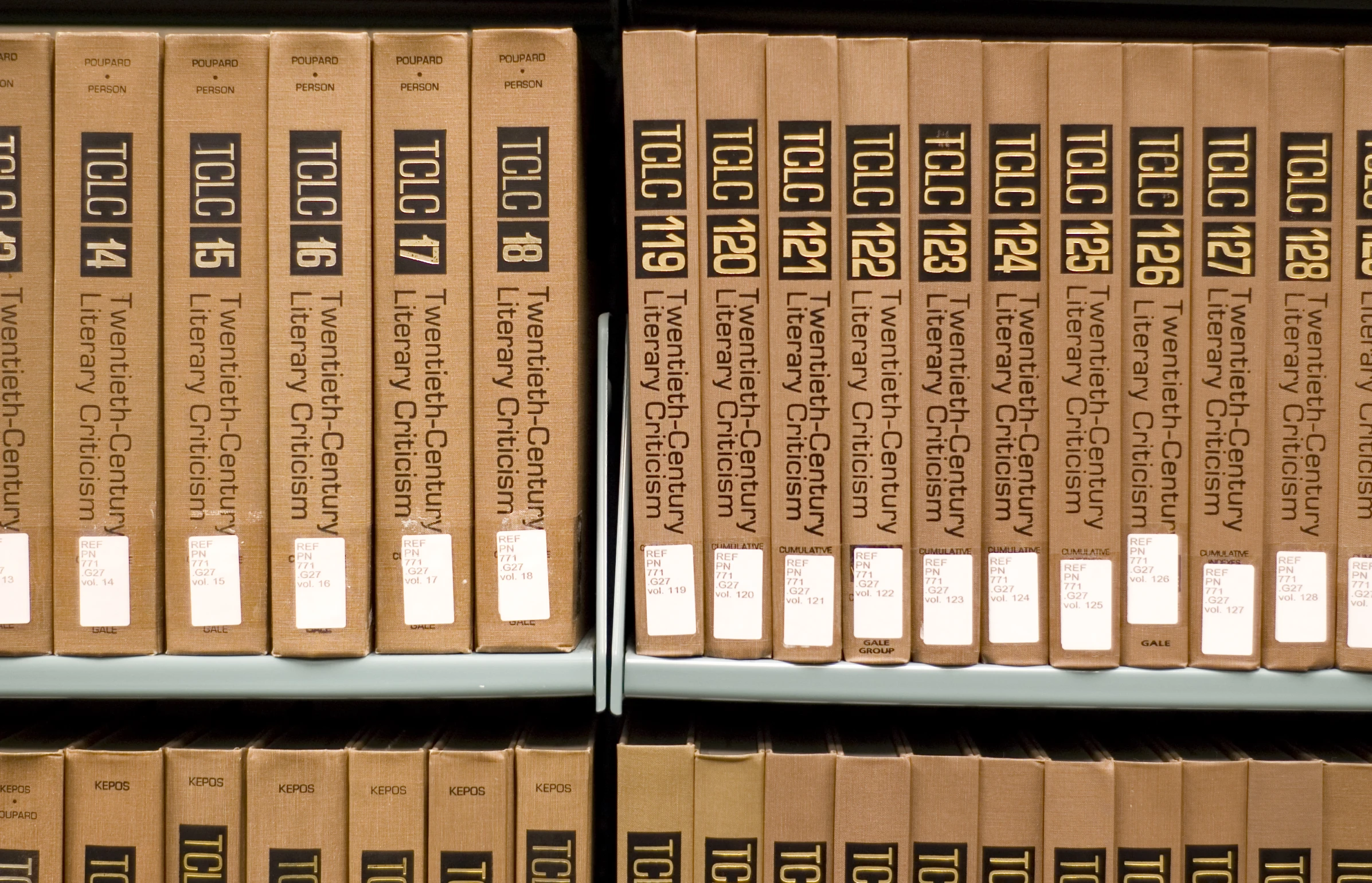 several old books in wooden shelves with white tags