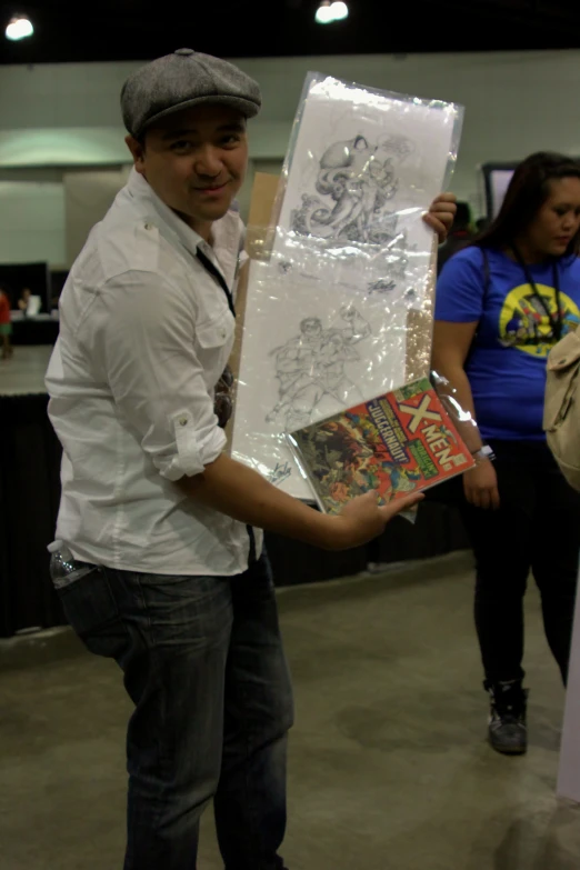 young man showing off comic style paintings at convention