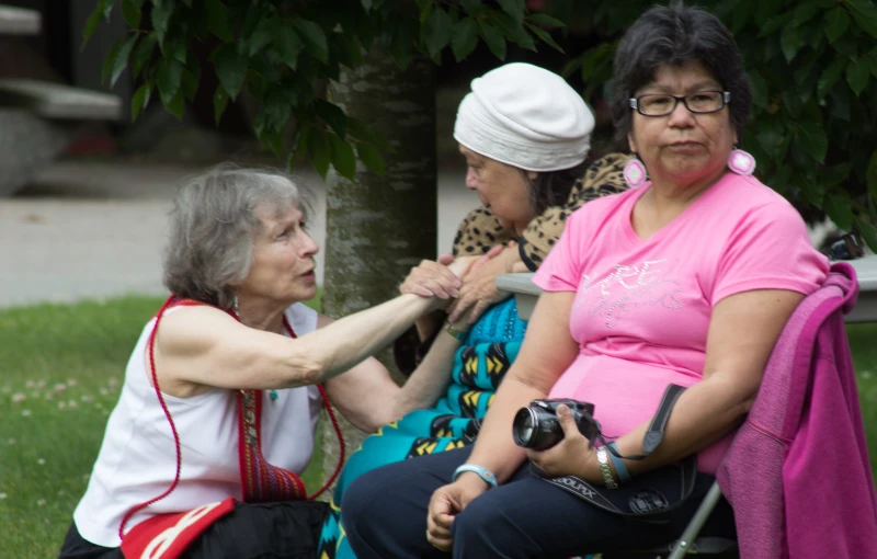 three woman sitting on a bench with cameras around