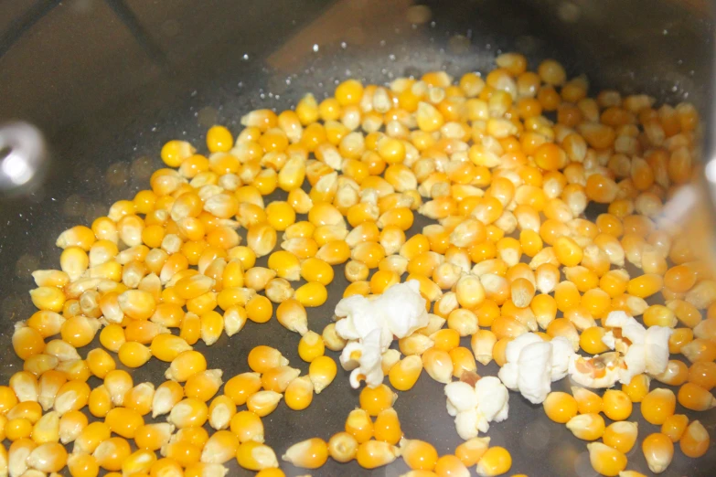 a mixture of raw corn and other food being cooked