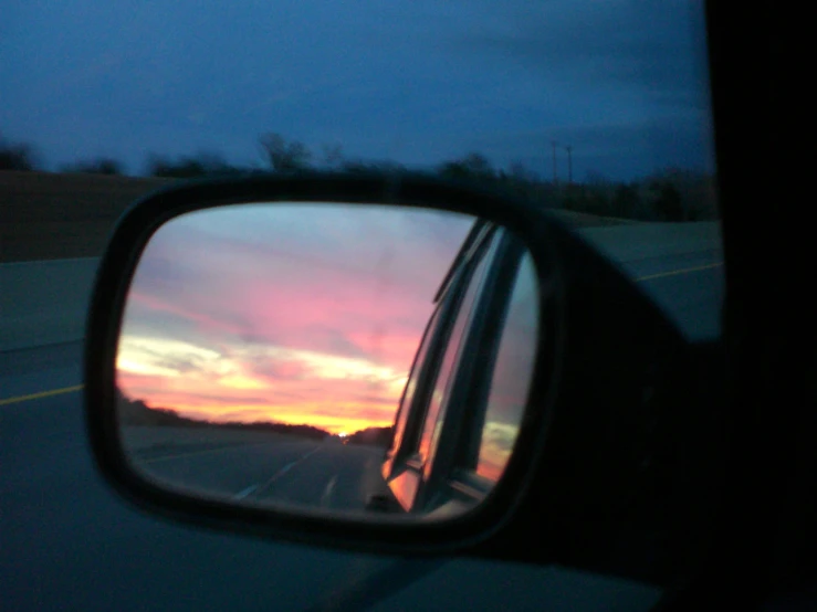 a view through a car window with the sun going down