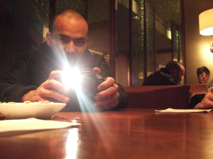 the man is sitting at the table and using his cellphone