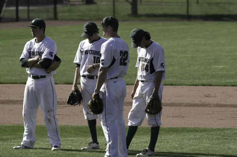 three baseball players standing on the field, one holding his glove and looking back