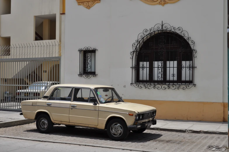 a brown car is parked next to a white building