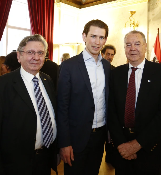 three people posing for the camera with another man dressed in suit