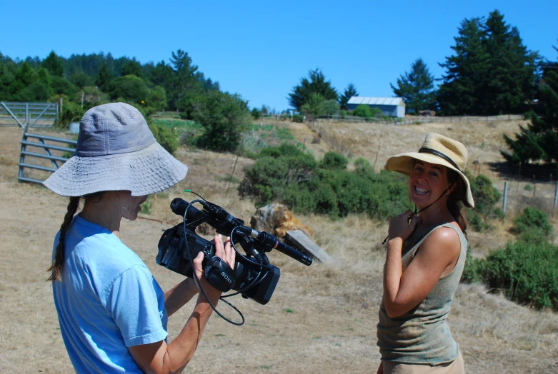 two women with hats talking in a field