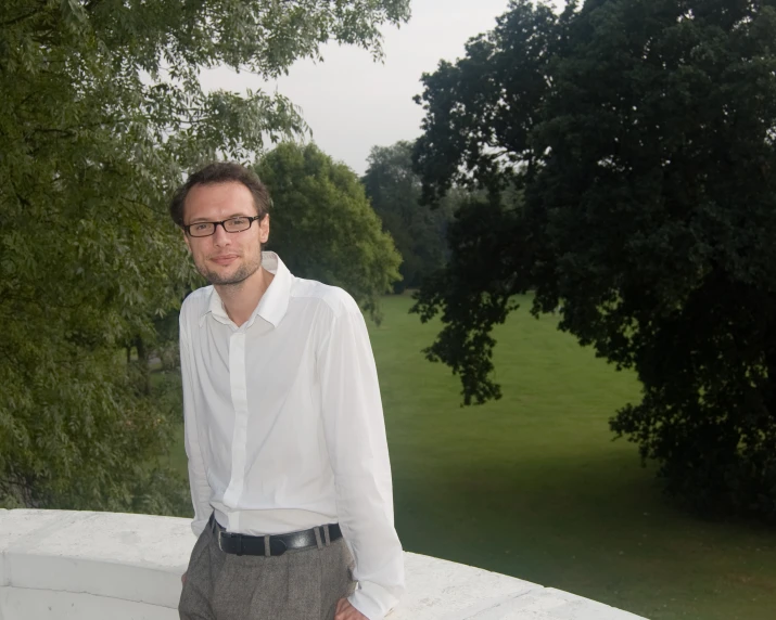 a man with glasses and shirt and tie is standing outside