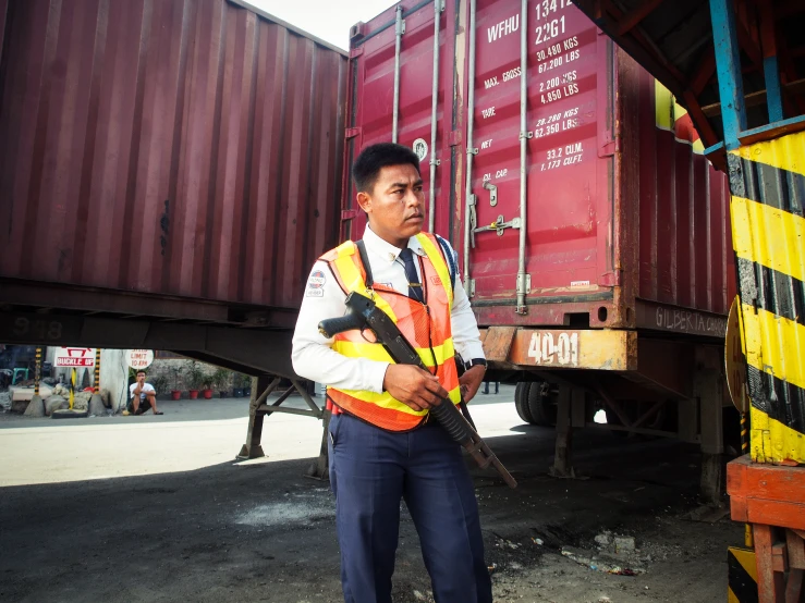 a man holding a gun while wearing a vest