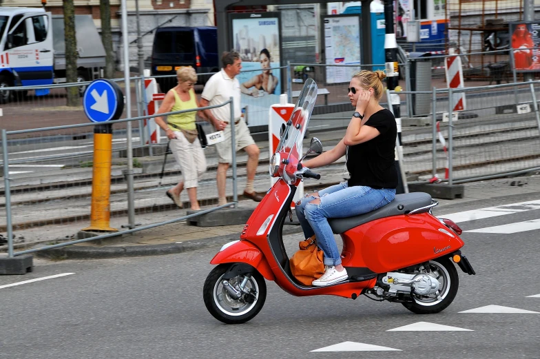 a woman with glasses sitting on a red scooter