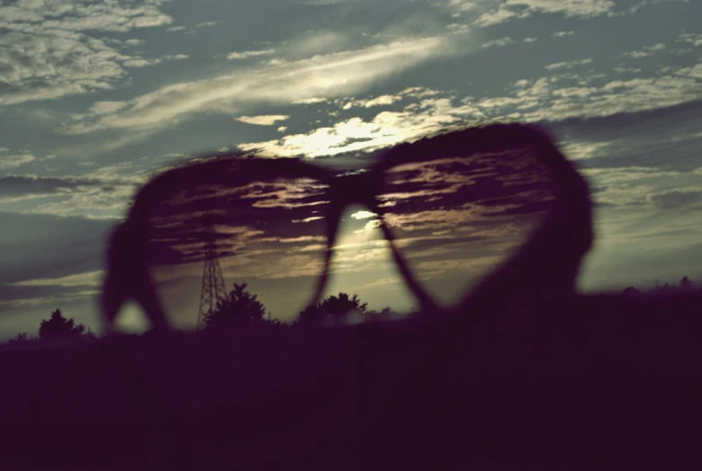 a dark colored po of two people silhouetted against the setting sun