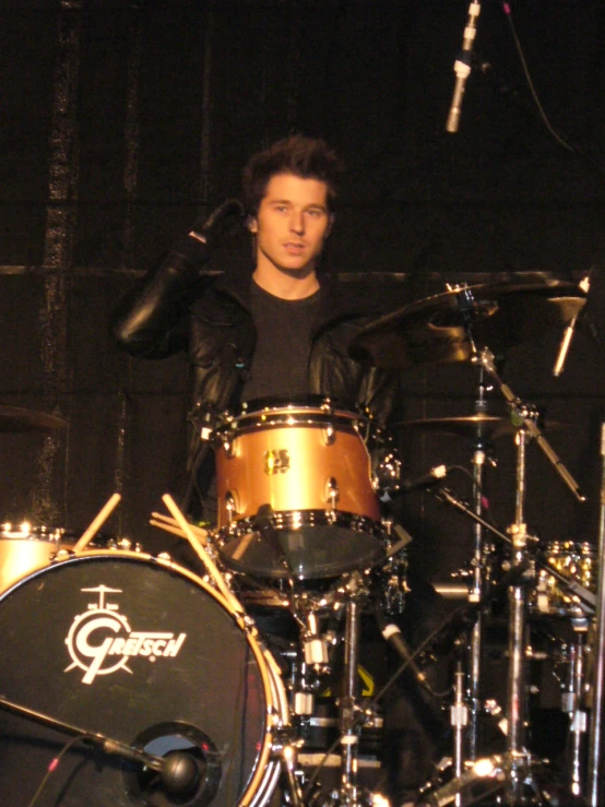 a young man plays the drums in front of a microphone