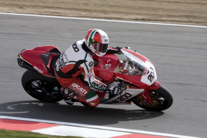 a person in helmet rides a red motorcycle around a corner