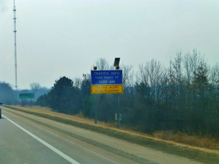 a blue and yellow sign by a road