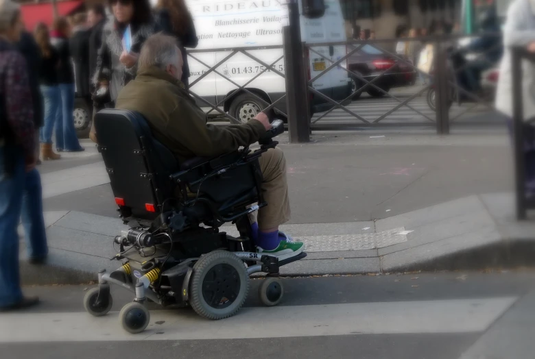 a man in a wheel chair riding down the street