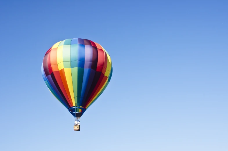 the large multi - colored balloon has a full blue sky background