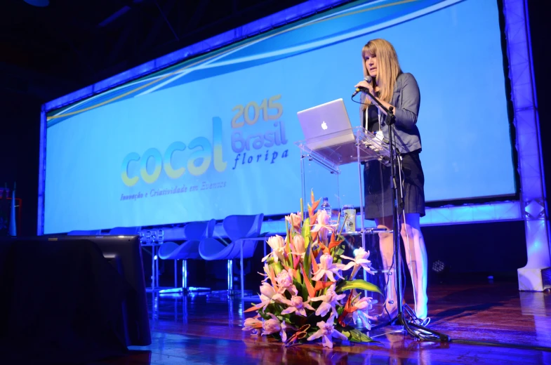 a woman is standing on stage with a laptop